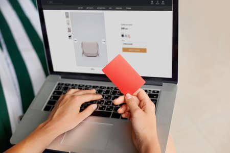 Young woman holding credit card and typing on laptop, shopping online home concept. Internet banking, spending moneyの写真素材