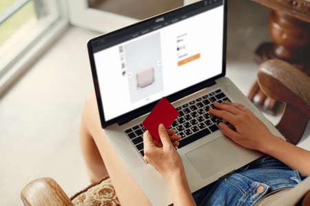 Woman is holding credit card and using laptop computer. Concept Shopping Online Technology. Working from homeの写真素材