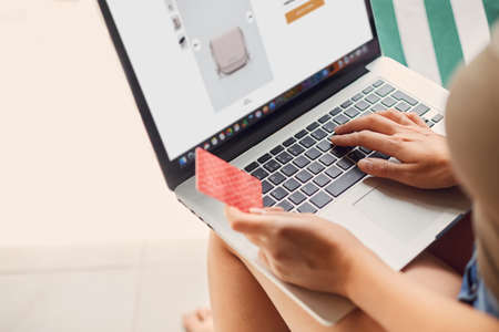 Woman is holding credit card and using laptop computer. Concept Shopping Online Technology. Working...