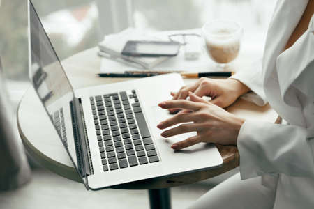 Closeup of a female hands busy typing on a laptop. Woman working at laptop computer hands close up. Working at home. Quarantine and Social distancing concept.の写真素材