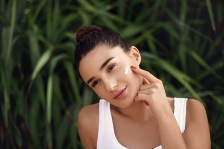 Beauty Woman face Portrait. Beautiful Spa model Girl with Perfect Fresh Clean Skin apply moisturizing cream. Skin care. Facial treatment.の写真素材
