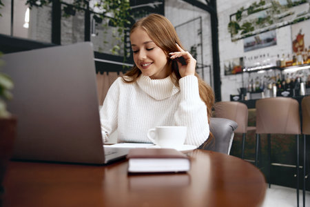Beautiful woman working on laptop while sitting in cafeの写真素材