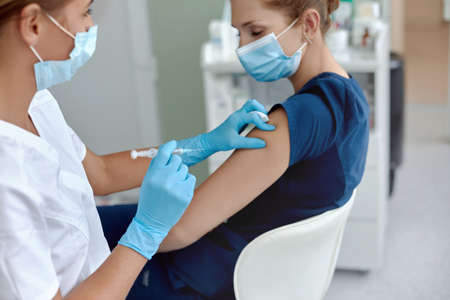 woman doctor or nurse giving shot or vaccine to patient shoulder.の写真素材