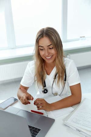 Female doctor make online video call consult patient on laptop. Medical assistant young woman therapist videoconferencing to webcam.の写真素材