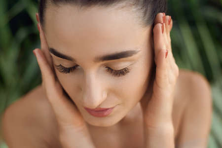 beauty concept. Beautiful Woman model With Long Eyelashes. Portrait of Girl in Tropical Leaves. Body And Skin care.の写真素材