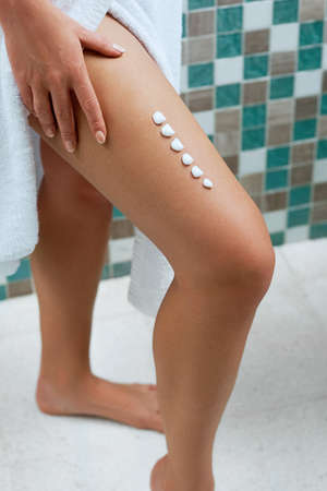 Cream on leg. Woman hand is applying moisturizing lotion on skin. beauty and body care.