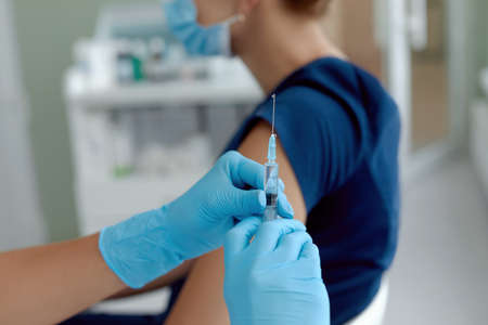 close up doctor holding syringe make injection to patient in medical mask. Covid-19 or coronavirus...