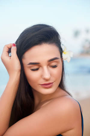 Close-up portrait of a smiling female by the sea. Happy woman standing at the seaside and looking awayの写真素材