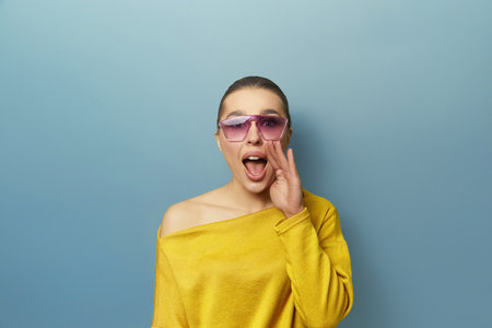 Portrait of shocked impressed woman with unexpected unbelievable reaction gesturing palm with wide open mouth isolated on blue backgroundの写真素材