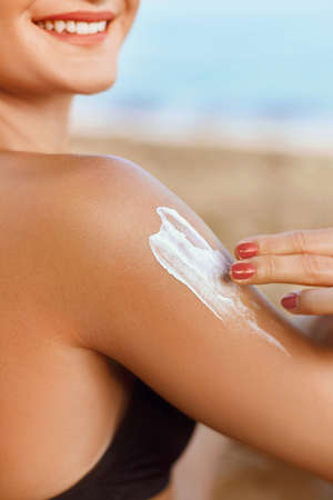 Woman in Bikini Applying Sunscreen Solar on Tanned Shoulder. sun cream. Skin and Body Care. Sun...
