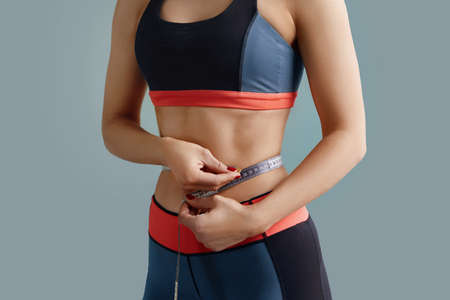 Woman measuring her waistline. Close up of female with perfect slim body. weight loss concept.の写真素材