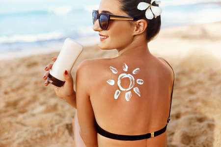 Woman Applying Sun Cream on Tanned Shoulder In Form Of The Sun. Sun Protection Sun Cream. Skin and...