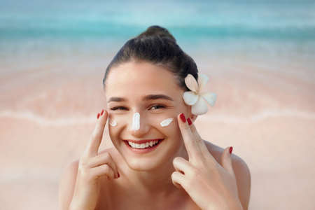 Beautiful Woman Face Portrait Beauty Skin Care Concept. Suncream. Suntan Lotion Beautiful Woman Applying on beautiful on Face. Sunscreen Solar Cream. Sun protection.The Girl Uses Moisturizer Sunblockの写真素材