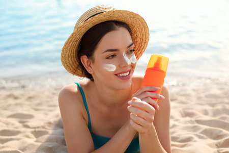 Beautiful woman applying cream sunscreen on tanned face. Sunscreen. Skin and body care. The girl...