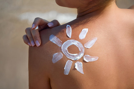 Sun Protection. Beauty Woman Applying Sun Cream on Tanned Shoulder In Form Of The Sun. . Skin Care....