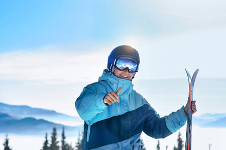 Portrait of a skier in the ski resort on the background of mountains and blue sky, Bukovel. Ski goggles of a man with the reflection of snowed mountains. wearing ski glasses. Winter Sportsの写真素材
