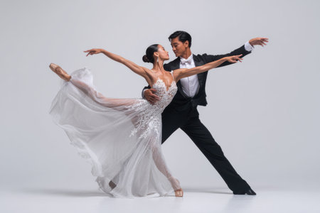Two skilled dancers express emotion through their movements, showcasing ballet technique in a sleek studio space with a simple background, emphasizing their artistry.の素材