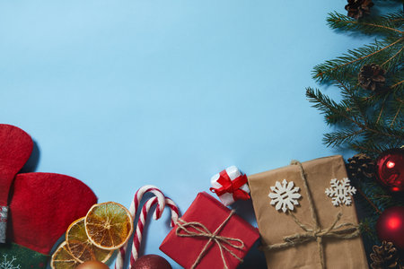Beautiful Christmas composition on blue background. Christmas present boxes, socks, fir spruce branches, conifer cones, caramel stick, gift. New Year. Top view, copy space.の写真素材