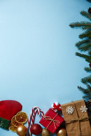 Beautiful Christmas composition on blue background. Christmas present boxes, socks, fir spruce branches, conifer cones, caramel stick, gift. New Year. Top view, copy space.の写真素材