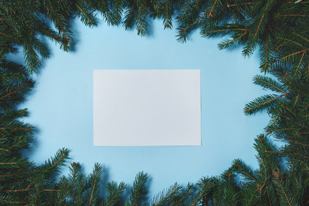 Layout made of Christmas tree branches with paper card note on blue background. Flat lay. Nature New Year concept.の写真素材