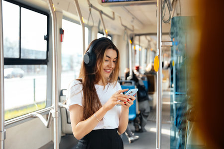Young woman listens to music on her smartphone while commuting in public transport, showcasing a...