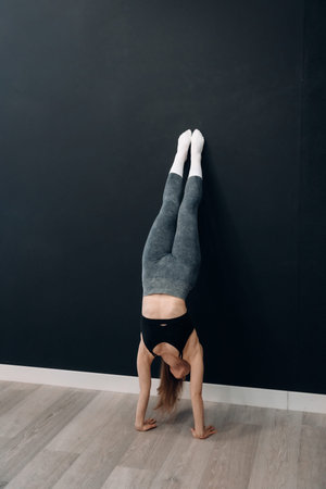 A young woman practices a seated side stretch in light activewear, smiling while exercising at a...