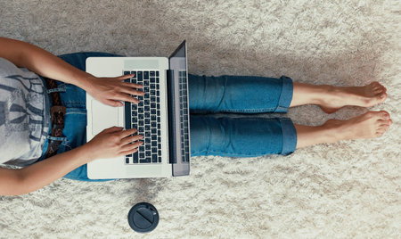 Woman working on a laptop. Female using a laptop sitting on floor, searching web, browsing...