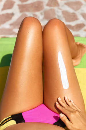 Woman applying sunscreen to her legsの写真素材