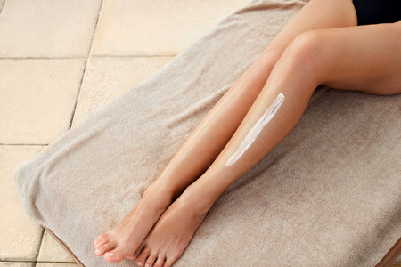 Cream on leg. Woman hand is applying moisturizing lotion on skin.