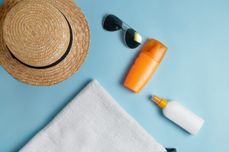 Beach flat lay accessories. Sun hat, towel, cream, sunscreen bottle, sun cream, lotion bottle,...