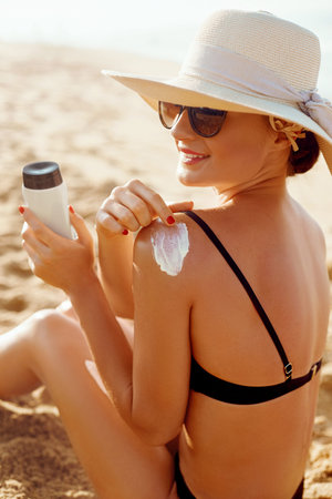 Beautiful Woman smile applying sun cream on shoulder. Skincare. Body Sun protection. sunscreen...