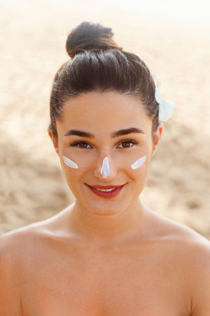 Beautiful Woman Face Portrait Skin Care Concept. Suncream. Suntan Lotion Beautiful Woman Applying on beautiful Face. Sunscreen Solar Cream. Sun protection. The Girl Uses Moisturizer Sunblockの写真素材