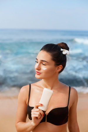 Suntan Lotion. Sexy Young Woman Applying Sunscreen Solar Cream on the beach.Sun Protection. Sun...
