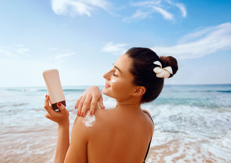 Woman apply Sun cream on tanned back. Skin and Body Care. Sun protection. Portrait of Female in...