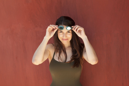 Cute latina girl wearing a dark swimsuit posing over a red wallの写真素材
