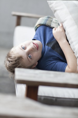 Lazy funny little child lying on sofa looking into cameraの写真素材