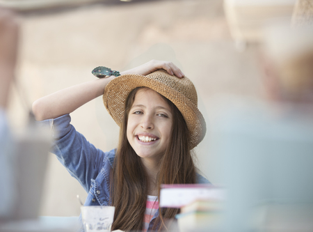 happy student wearing straw hat and a hand on his headの写真素材