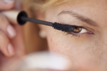 Portrait of a gorgeous female putting mascara on her eyesの写真素材