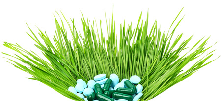 Pills, tablets and wheat grass in the basket on white
