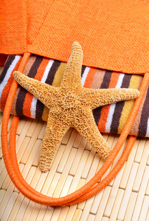 Beach bag with towel and starfish on a wooden backgroundの写真素材