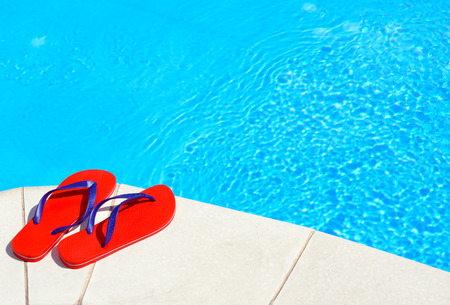 Pair of red flip-flops on the swimming pool