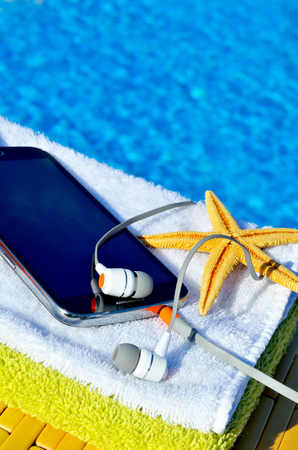 Bath towels, cell phone, starfish near the swimming poolの写真素材