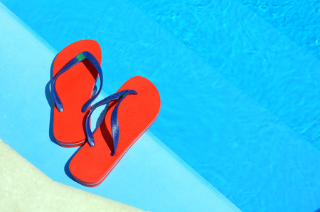 Pair of red flip-flops on the swimming pool