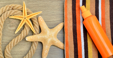 Starfish, color towel and sunscreen spray against on wooden background.の写真素材