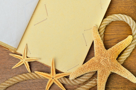 Vintage book or photo album with empty photo frames and starfish on wooden background.の写真素材