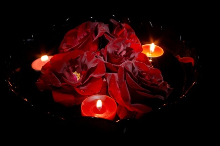 Red roses with candles on blackの写真素材