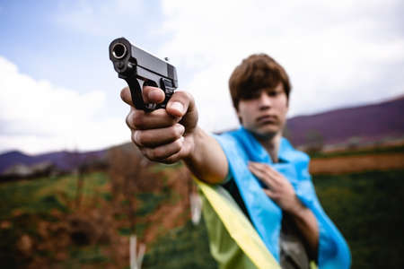 The guy pointed the gun. No war in Ukraine. Background sky and mountains.の写真素材