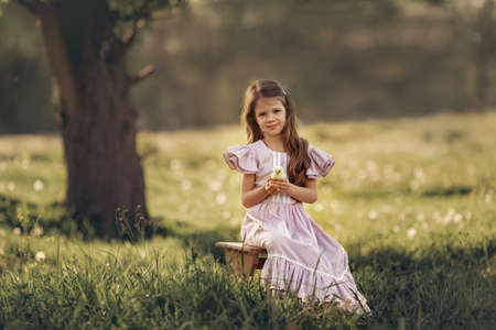 A girl in vintage clothes holds a little chicken in her hands.