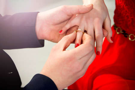 A man proposes to a girl. Close-up hands. He puts the ring on her finger.の写真素材