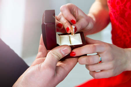 A man proposes to a girl. Close-up hands. The girl is holding a ring in a box.の写真素材